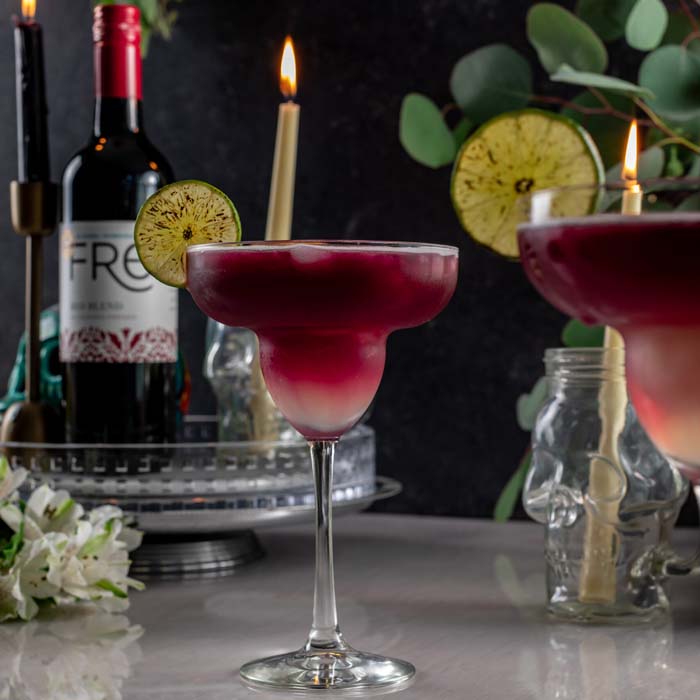 dark photo of a deep red mocktail in front of a bottle of FRE Alcohol-Removed Red Blend
