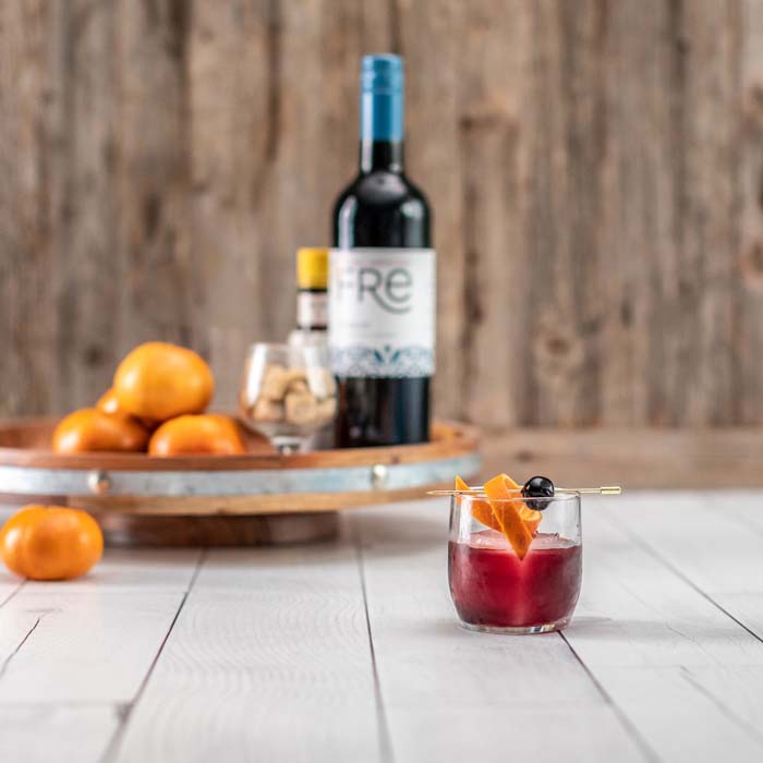 Color image of a bottle of FRE Alcohol-Removed Merlot next to a red cocktail