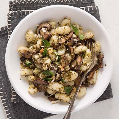 Bird's eye view of a bowl of gnocchi with mushrooms and herbs